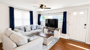 A living room with a sofa, TV, and a ceiling fan.