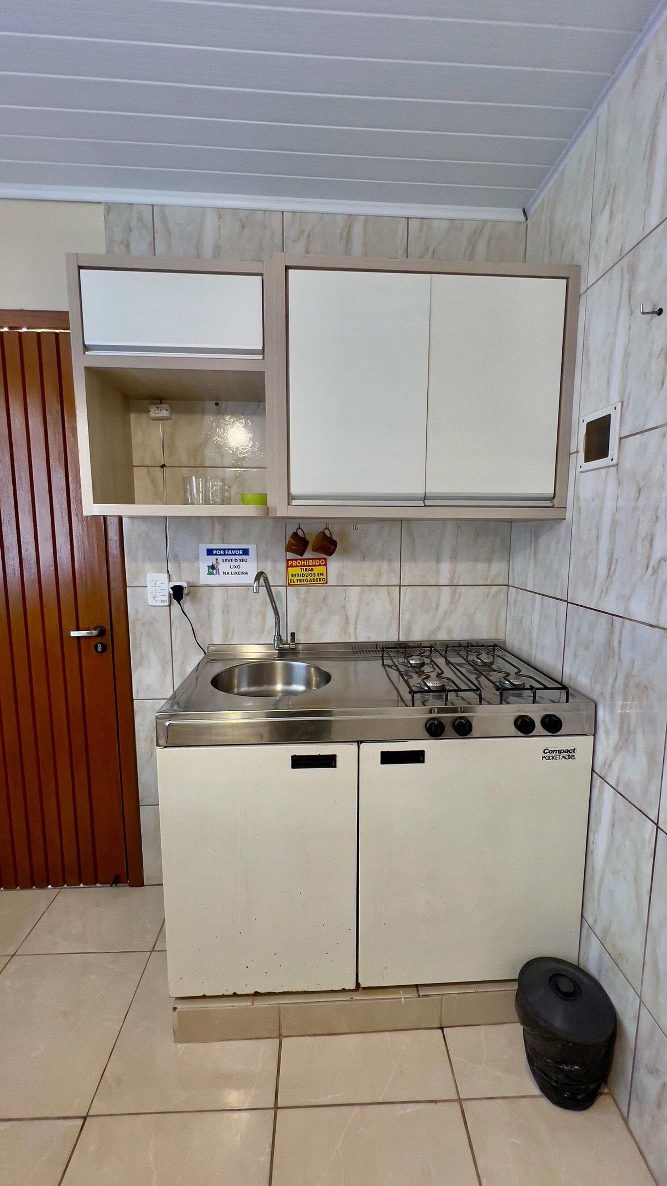 Una kitchenette compacta con lavamanos, estufa y armarios.