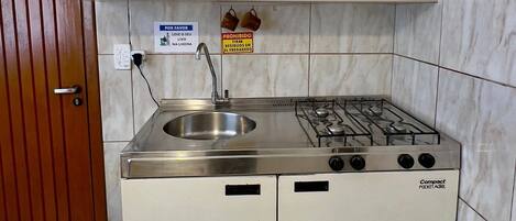 Una kitchenette compacta con lavamanos, estufa y armarios.