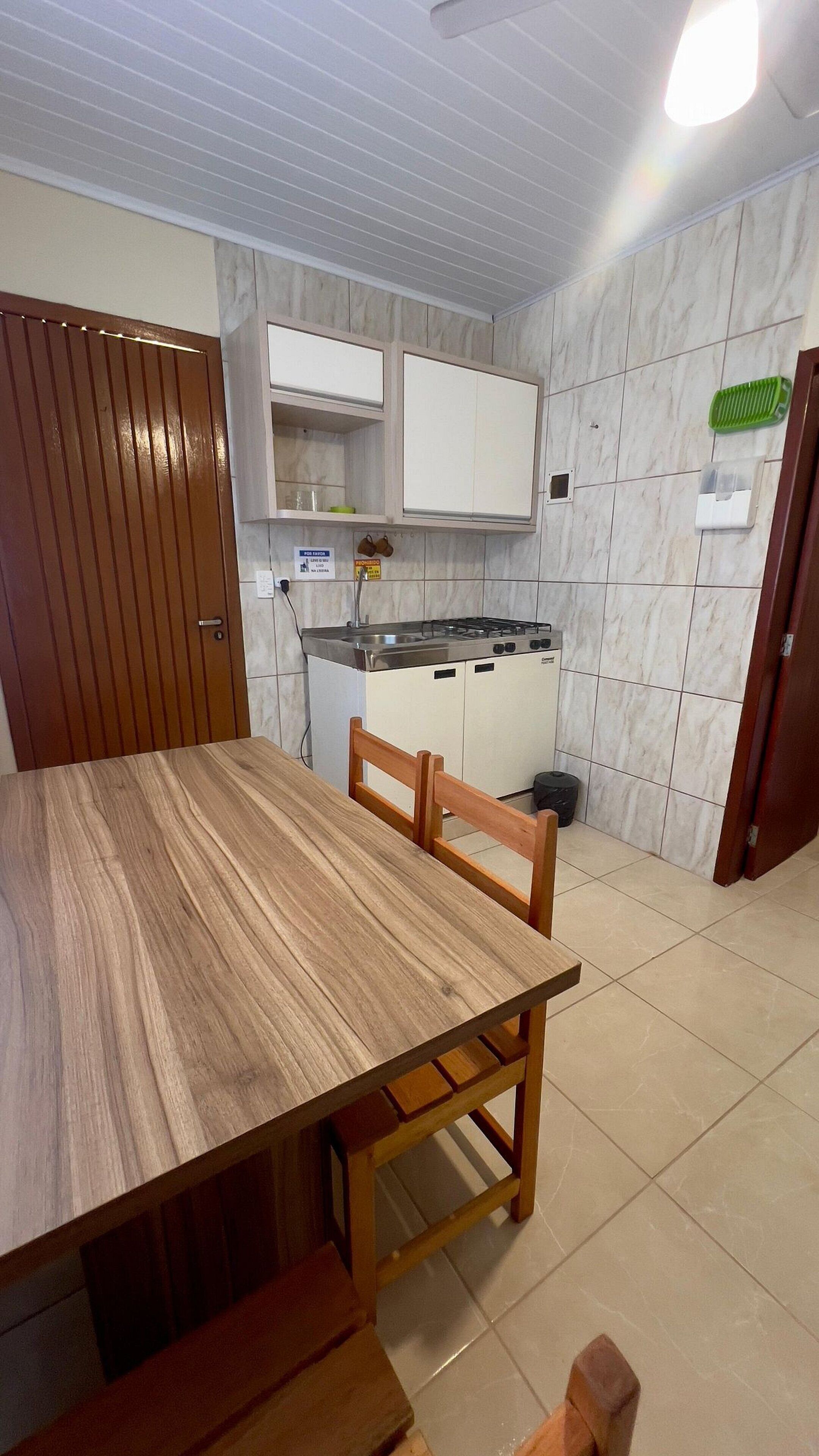 A kitchen with a wooden table and chairs, a stove, cabinets, and a tiled backsplash.