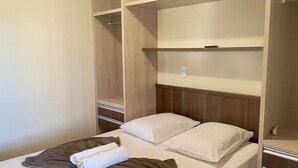 Ett hotellrum med en säng, en garderob i trä och en taklampa.