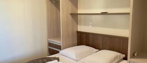 Una habitación de hotel con una cama, un armario de madera y una lámpara en el techo.