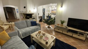 A living room with a sofa, coffee table, TV, and a small Christmas tree. - Spacious house with garden (Sanary-sur-Mer)