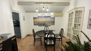 A dining area with a round table, four chairs, a ceiling light fixture, and a large window with a view of the beach. - Spacious house with garden (Sanary-sur-Mer)