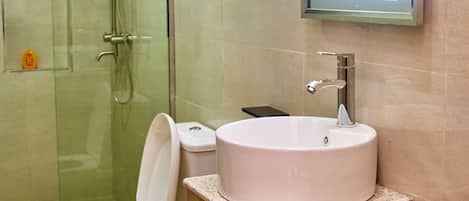 A bathroom with a glass-enclosed shower, a white toilet, a wooden vanity with a sink, and a mirror with a light.