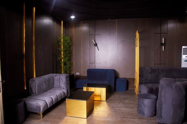 Una sala moderna con un sofá, dos mesas de centro doradas y un sillón azul de acento.