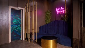A modern room with a blue sofa, a gold-framed window, and a neon sign. - De Mipos Luxury Suites (Abuja)