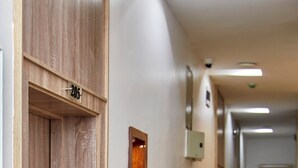 A hallway with a wooden door labeled "205", a framed picture on the wall, and a security camera. - De Mipos Luxury Suites (Abuja)