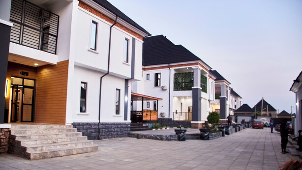 A residential street with modern houses, a paved walkway, and a small park area. - De Mipos Luxury Suites (Abuja)