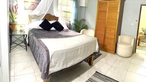 Una camera da letto con un letto, un comodino, una lampada, piante in vaso e un armadio.