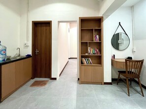 Cocina compacta con un mueble de madera, un lavamanos y un dispensador de agua.