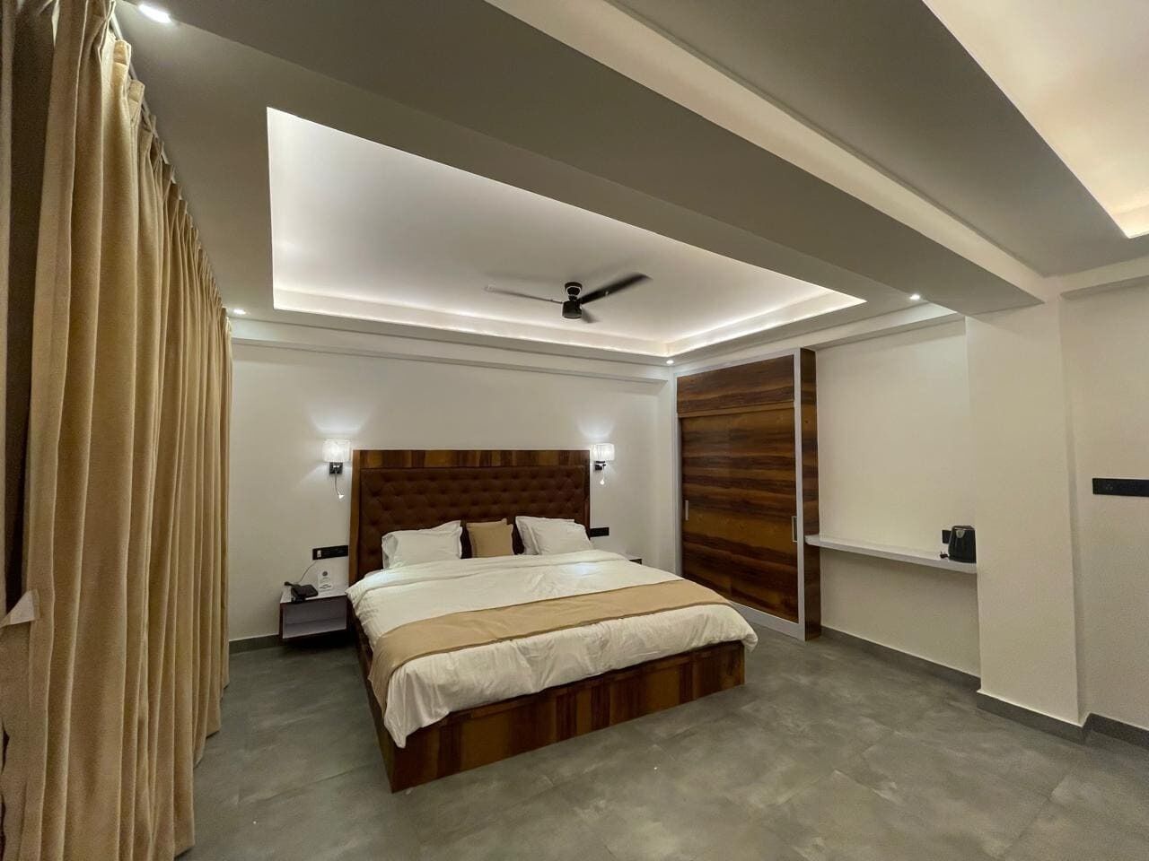 Un dormitorio moderno con una cama grande, un ventilador de techo y un panel de pared de madera empotrado.