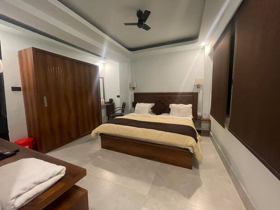 Una habitación de hotel con cama, escritorio, armario y ventilador de techo.