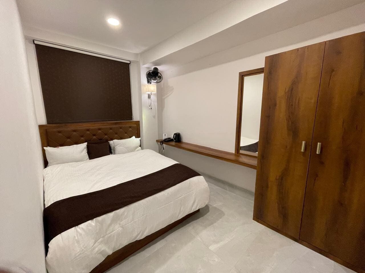 A bedroom with a bed, a wardrobe, a bedside table, and a mirror.