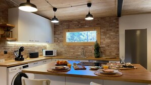 A modern kitchen with a wooden island, white cabinetry, a built-in microwave, and a stainless steel refrigerator.