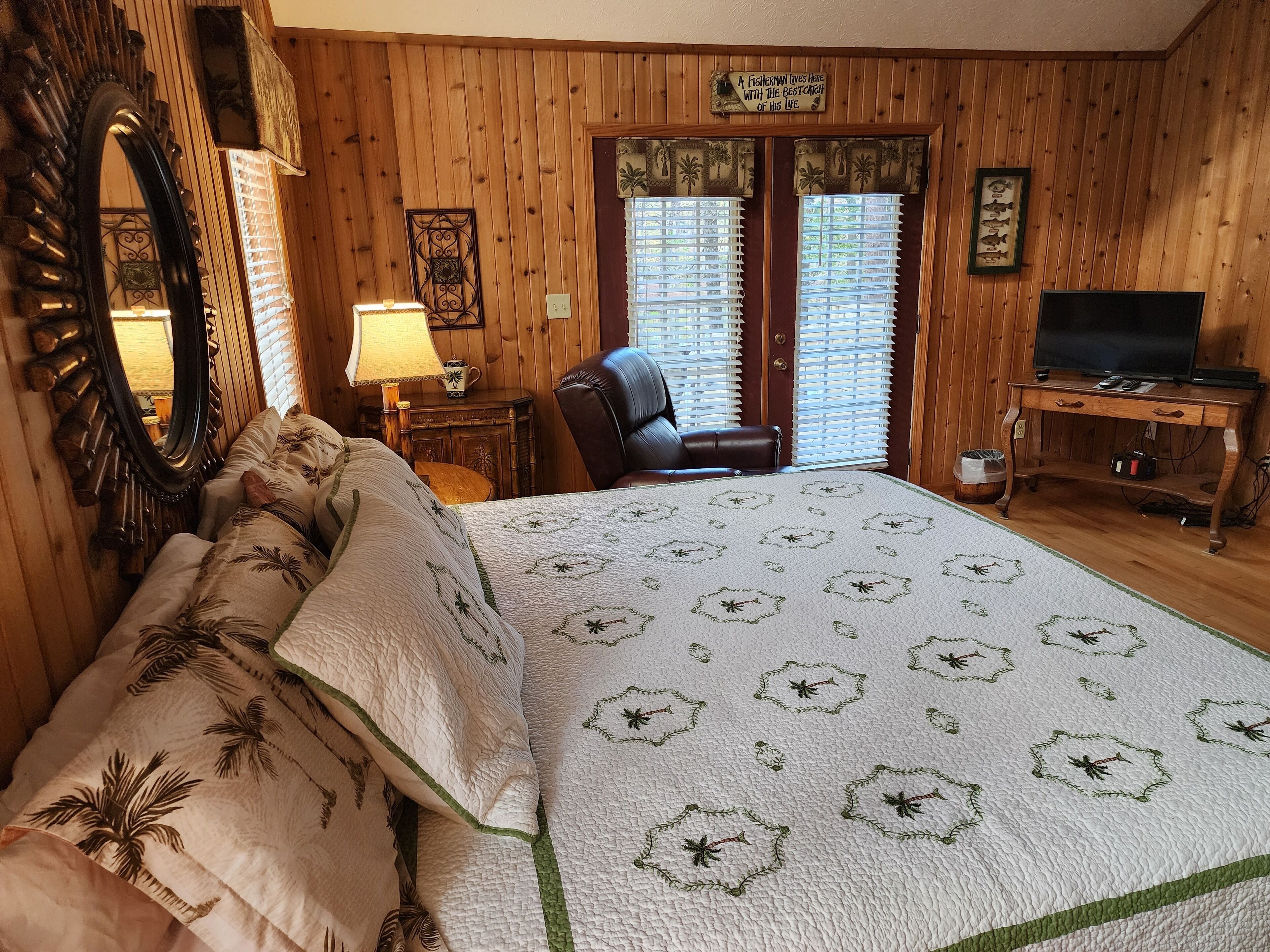 Een kamer met houten lambrisering, een bed, een bureau, een stoel en een televisie.