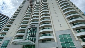 A high-rise building with multiple balconies and a central entrance with a glass facade. - OZPED Flats Particulares Biarritz (Brasília)