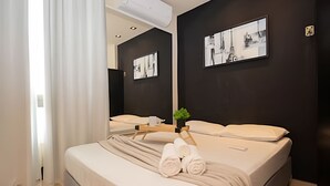 A modern hotel room with a large bed, a bedside table, a mirror, and a wall-mounted picture. - OZPED Flats Particulares Biarritz (Brasília)