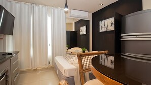 A modern kitchen with a dining area, white curtains, and a flat-screen TV. - OZPED Flats Particulares Biarritz (Brasília)