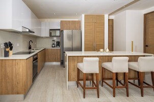 Una cocina moderna con armarios de madera, un refrigerador de acero inoxidable y una encimera blanca.