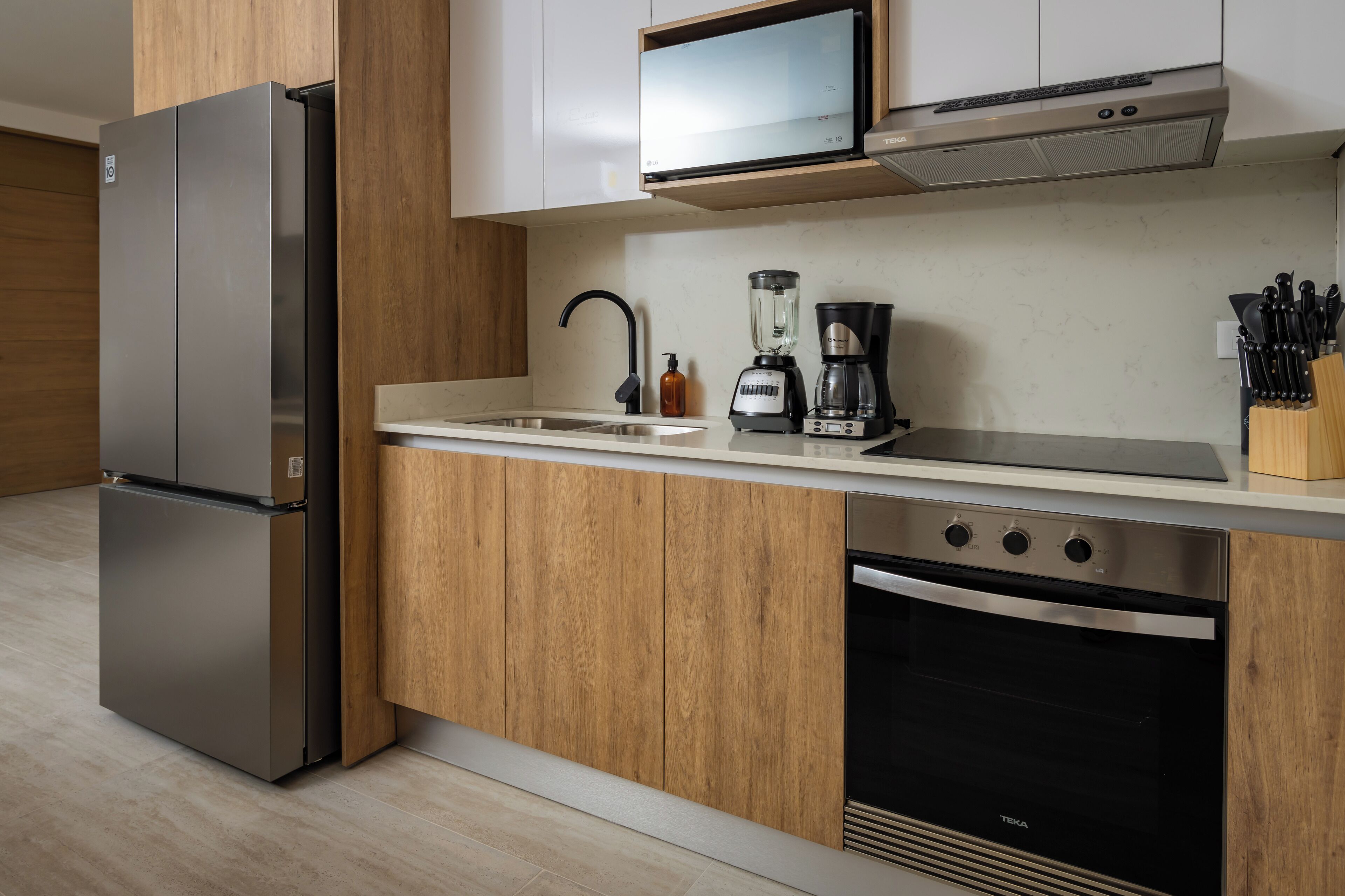 Una cocina moderna con refrigerador de acero inoxidable, microondas, cafetera y lavavajillas.