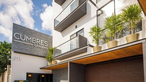 Un edificio moderno con un letrero que dice "CUMBRES GARDENS" y una puerta de garaje.