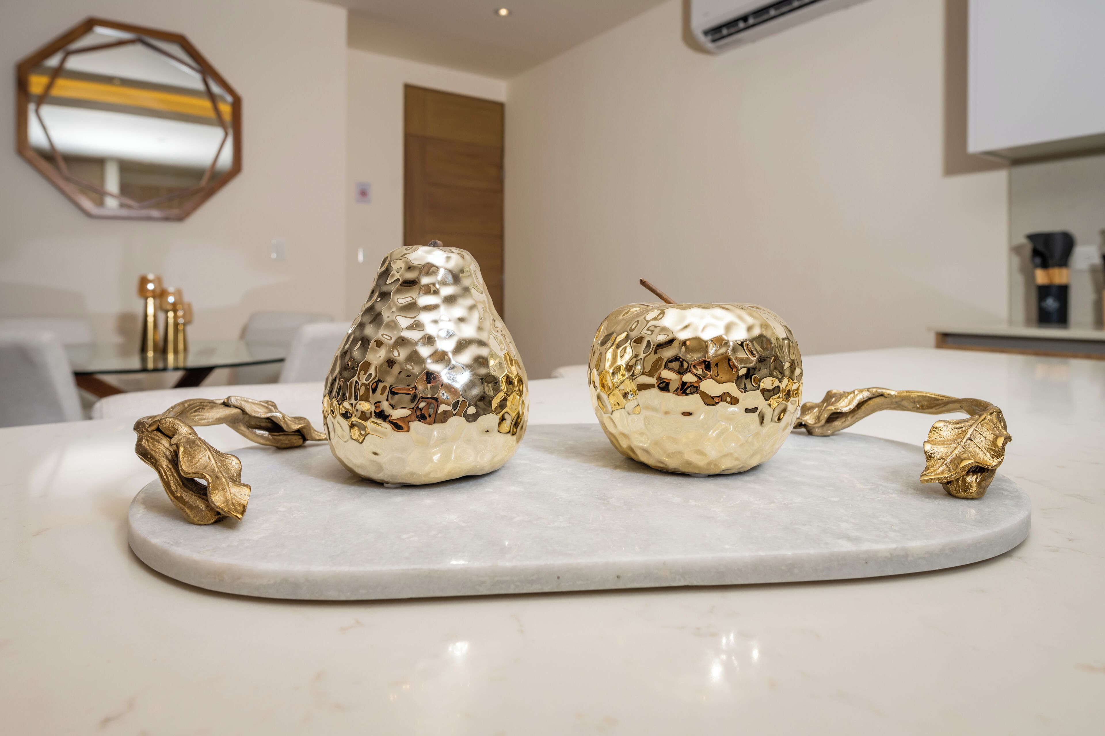 Two decorative golden vases on a marble countertop in a modern kitchen setting.