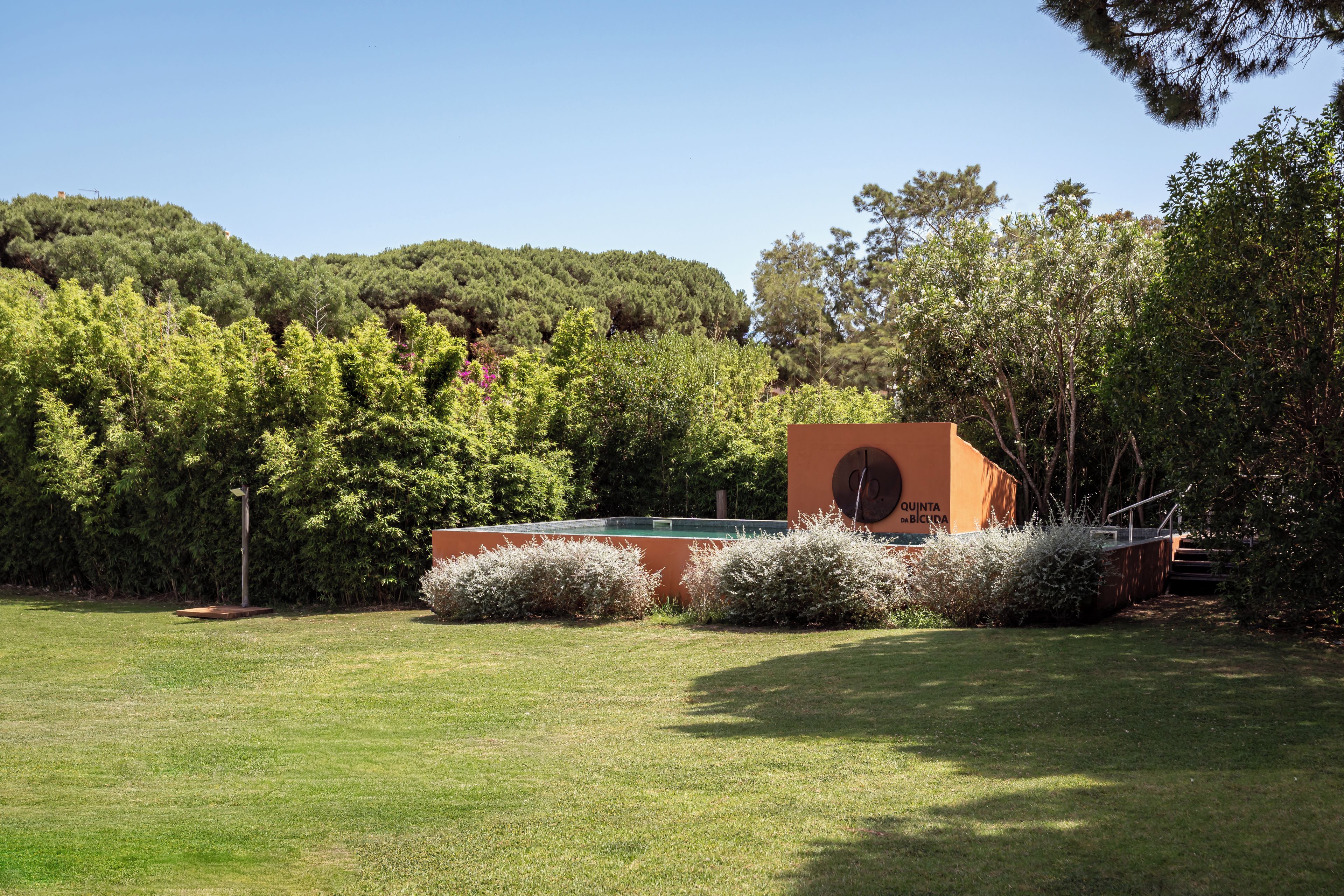 Un edificio con una finestra circolare e un cartello che riporta la scritta 'QUINTA DA BICIDA', immerso in una zona erbosa con alberi.