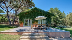 An outdoor patio with a wooden table and chairs, a white umbrella, and a concrete staircase leading to a glass door. - Quinta da Bicuda (Cascais)