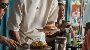 A person serving food at a table with a glass of orange juice and a bottle of water. - Quinta da Bicuda (Cascais)