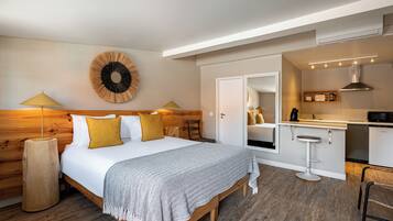 A modern bedroom with a wooden headboard, a large bed with a patterned throw, two bedside lamps, and a wall-mounted circular decoration.
