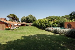 A residential property with a well-maintained lawn, a swimming pool, and a large tree.