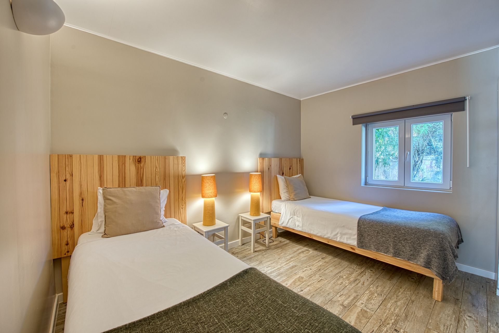 A bedroom with two beds, a window, and a lamp.