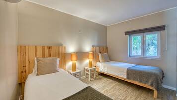 A bedroom with two beds, a window, and a lamp.