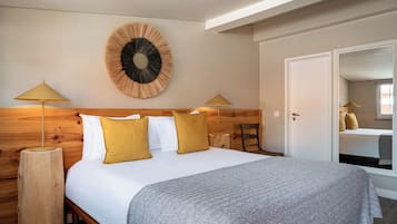 A bedroom with a wooden headboard, a round wall decoration, two bedside lamps, and a bed with white and mustard pillows.