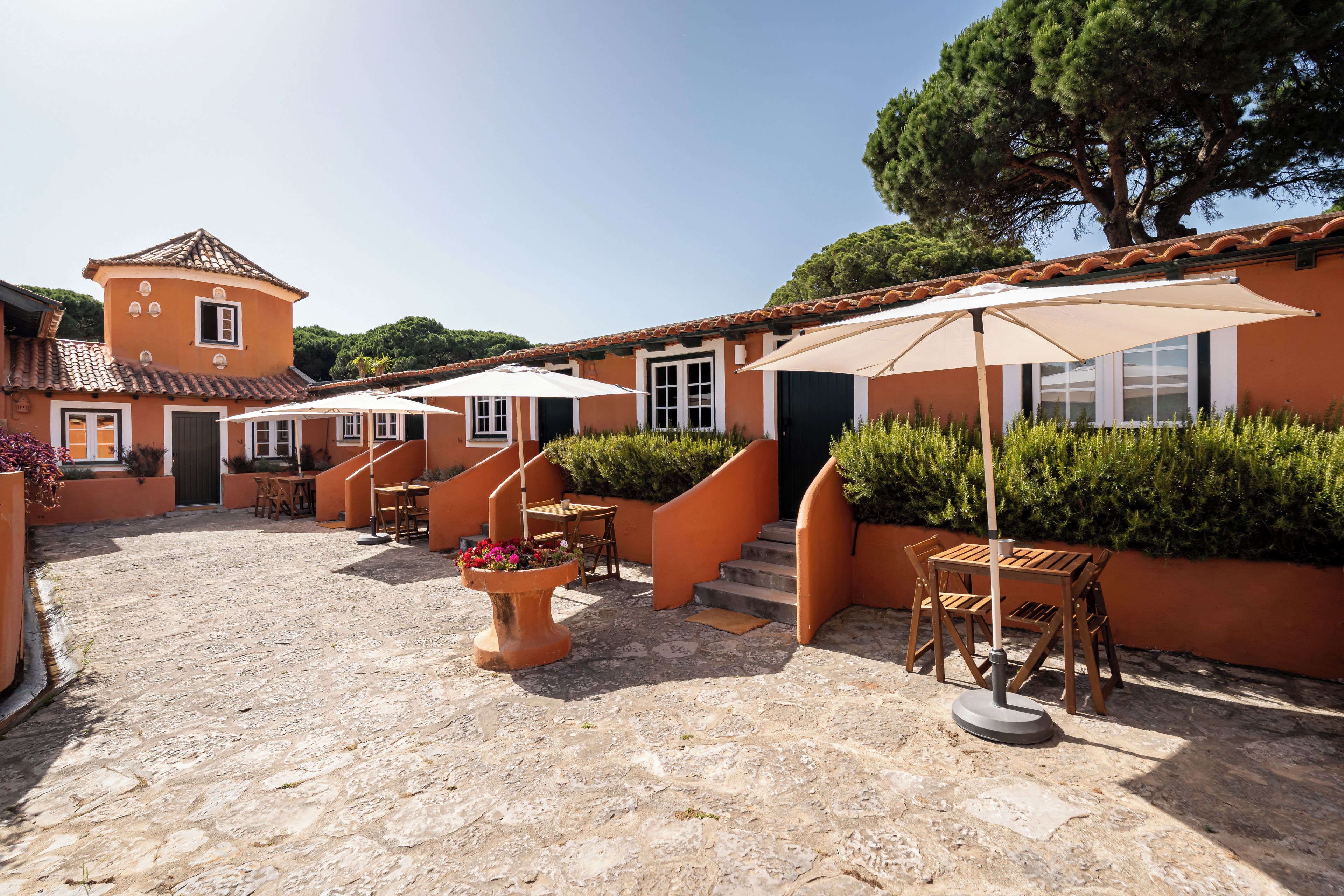A courtyard with outdoor seating, a staircase, and a building with a tiled roof.