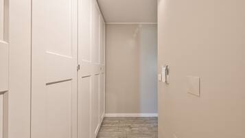 A narrow hallway with white doors, a wooden floor, and a light switch on the wall.