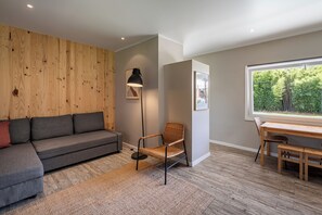 Una sala de estar moderna con un sofá gris, una silla de mimbre, una lámpara de pie y un muro de madera.