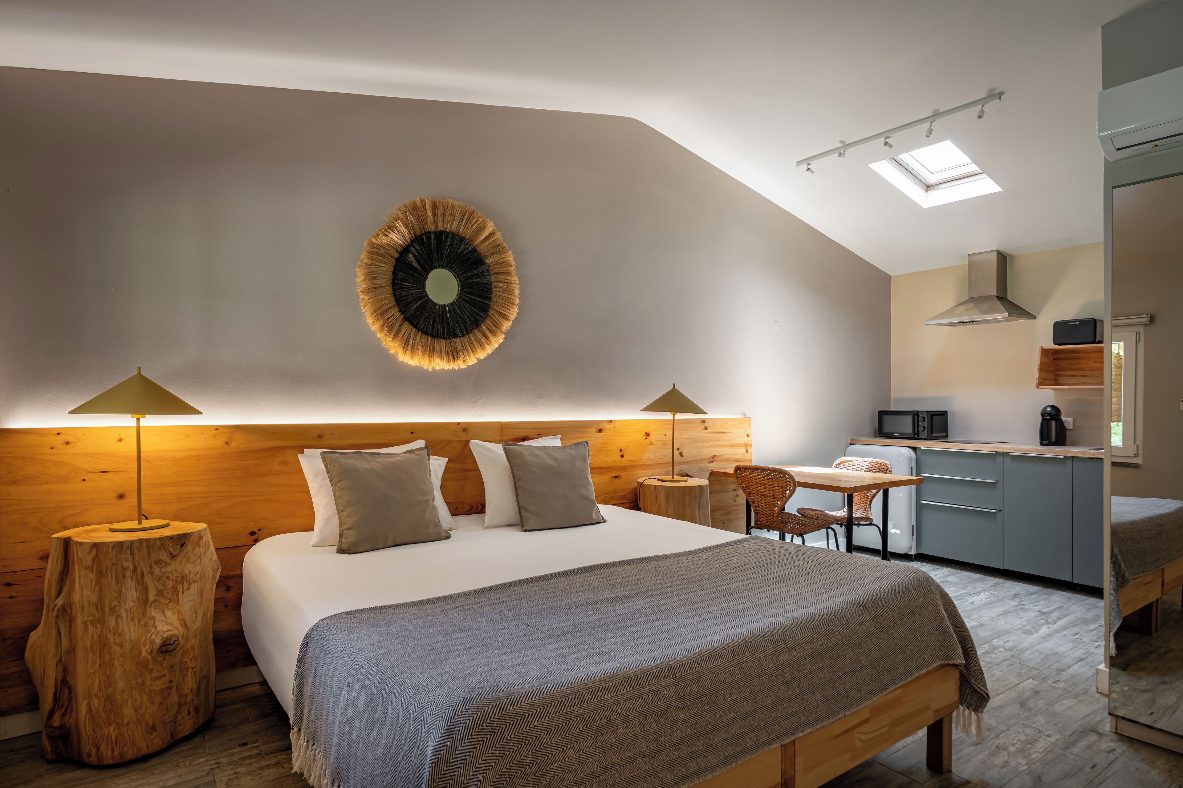 Un dormitorio moderno con una cama grande, lámparas de noche, cabecera de madera y un adorno circular en la pared.