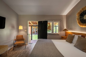 Un dormitorio con cama, una silla, una lámpara y vistas a un espacio exterior.