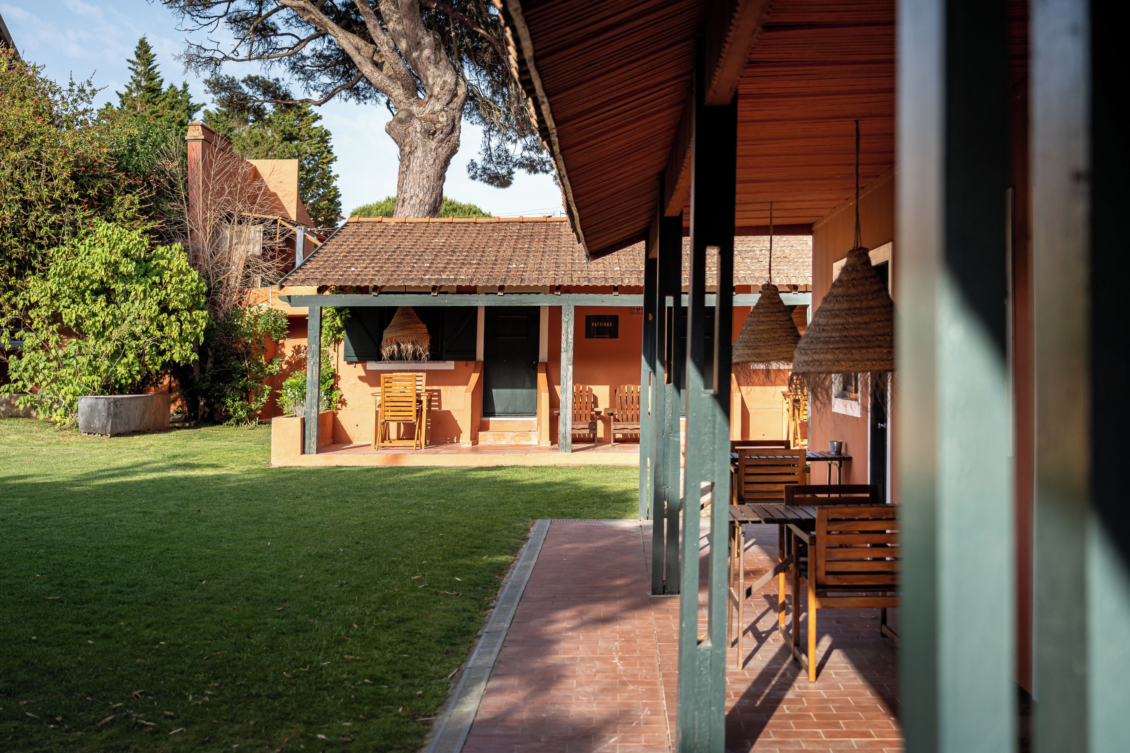 A building with a covered patio area, outdoor seating, and a well-maintained lawn.