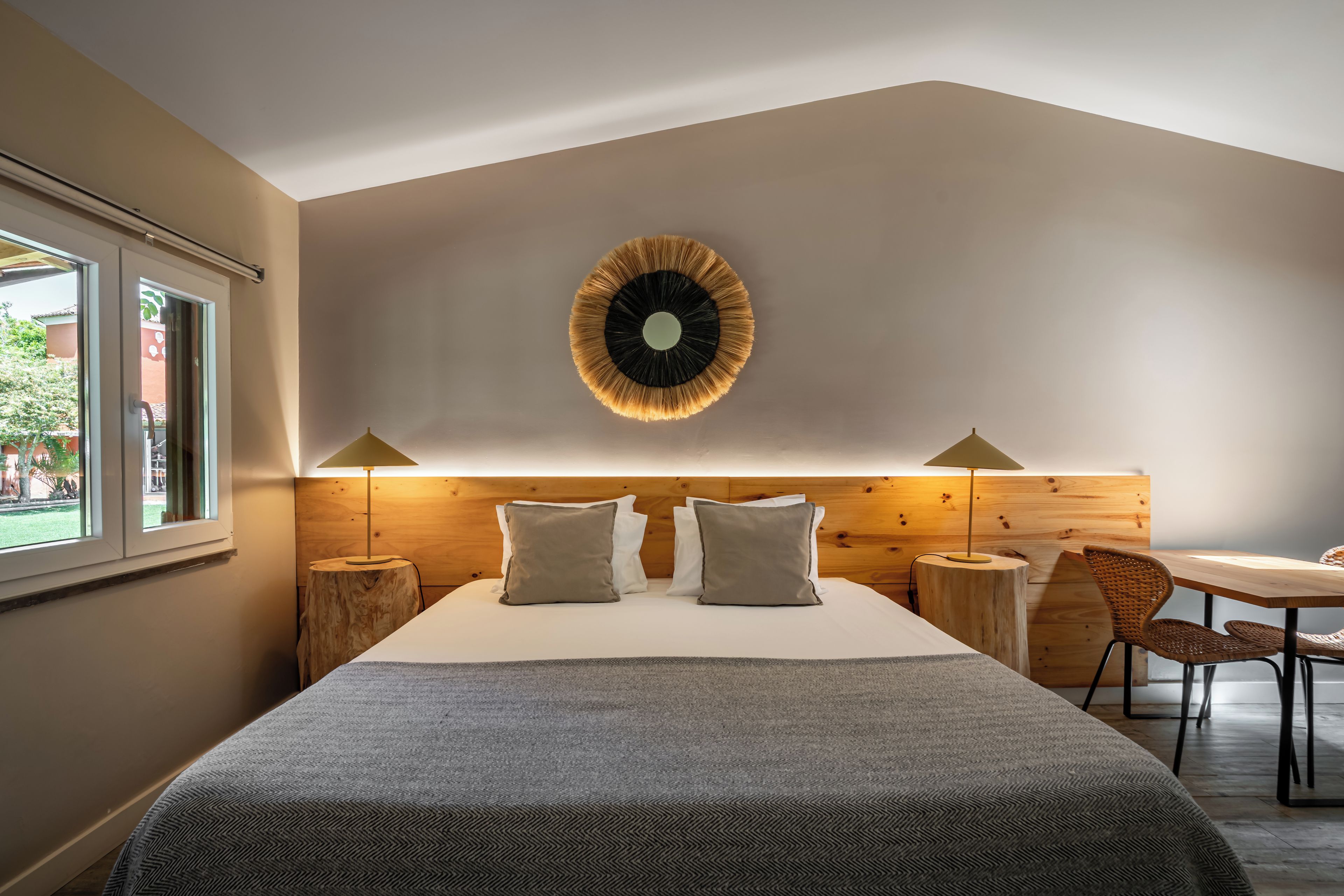 Un dormitorio moderno con una cama grande, un reloj de pared redondo y una zona de comedor con mesa y sillas.
