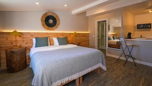 A bedroom with a wooden headboard, a bed with a patterned bedspread, a bedside lamp, and a small wooden stool. - Quinta da Bicuda (Cascais)
