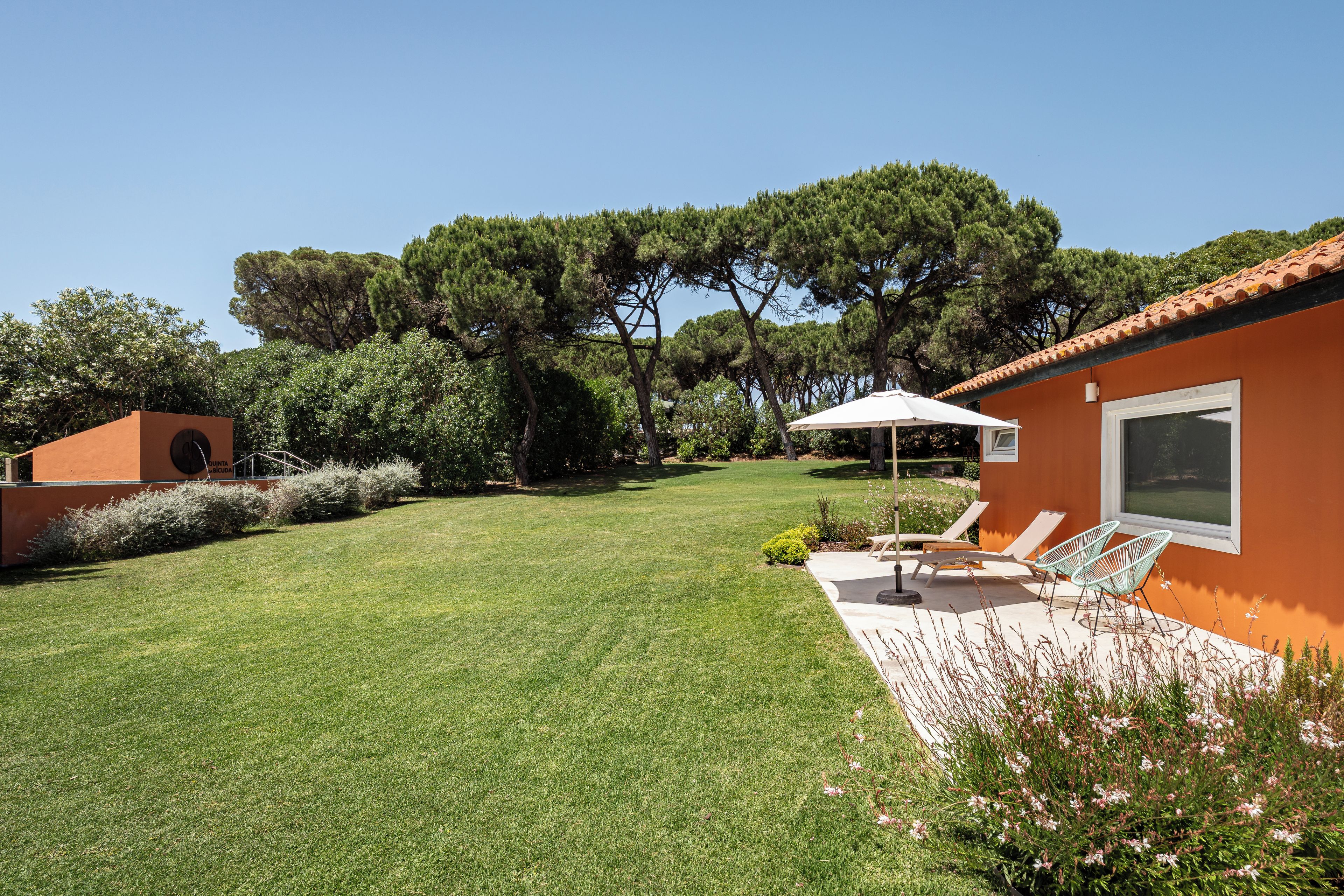 A well-maintained lawn with a patio area, outdoor furniture, and a view of a forested area.