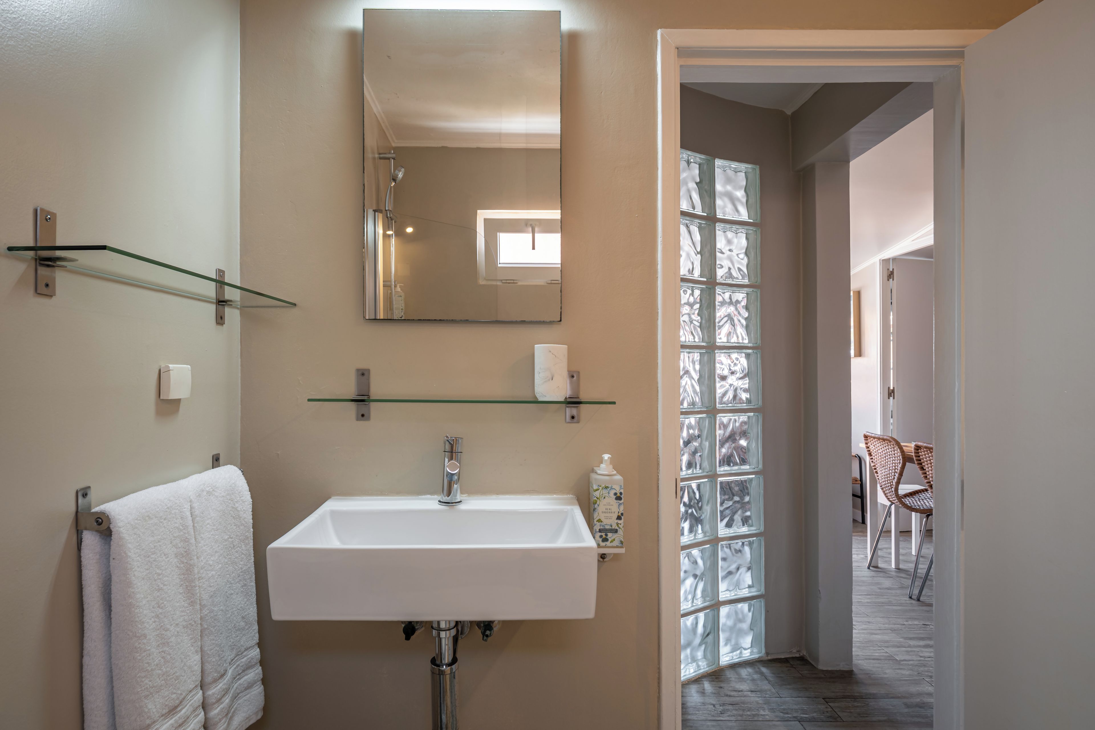 A bathroom with a white sink, a towel rack, a mirror, and a glass shower enclosure.