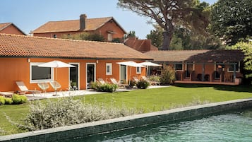 A residential property with a swimming pool, outdoor seating, and a well-maintained lawn.