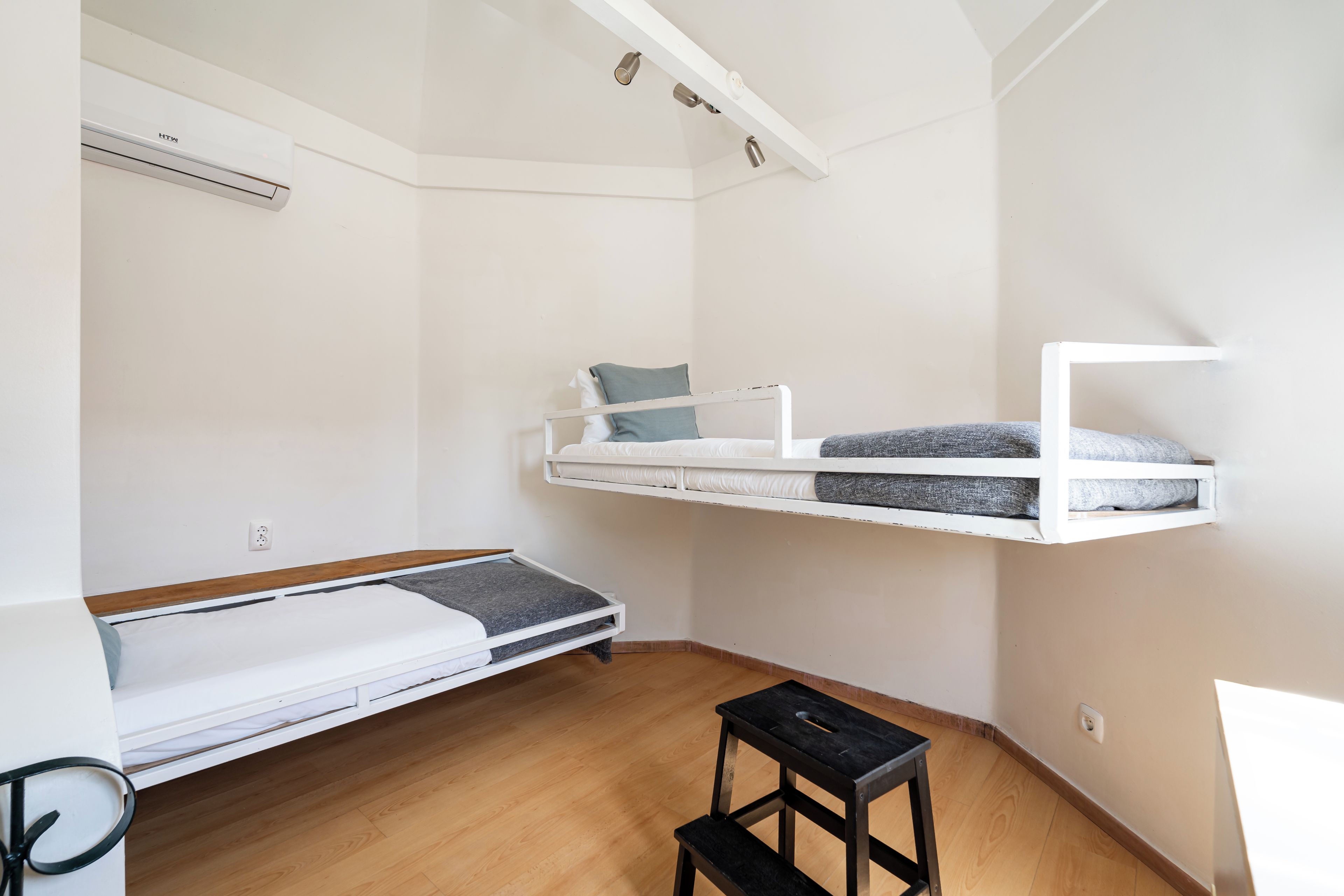 A compact room with a bunk bed, a small table, and a desk.