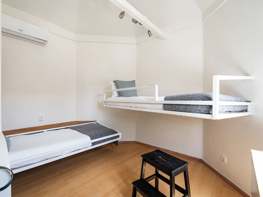 Ein kleines Zimmer mit Etagenbett, Tisch und Schreibtisch.