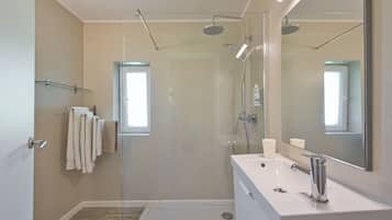 A modern bathroom with a glass shower enclosure, a white sink with a mirror, and a towel rack.