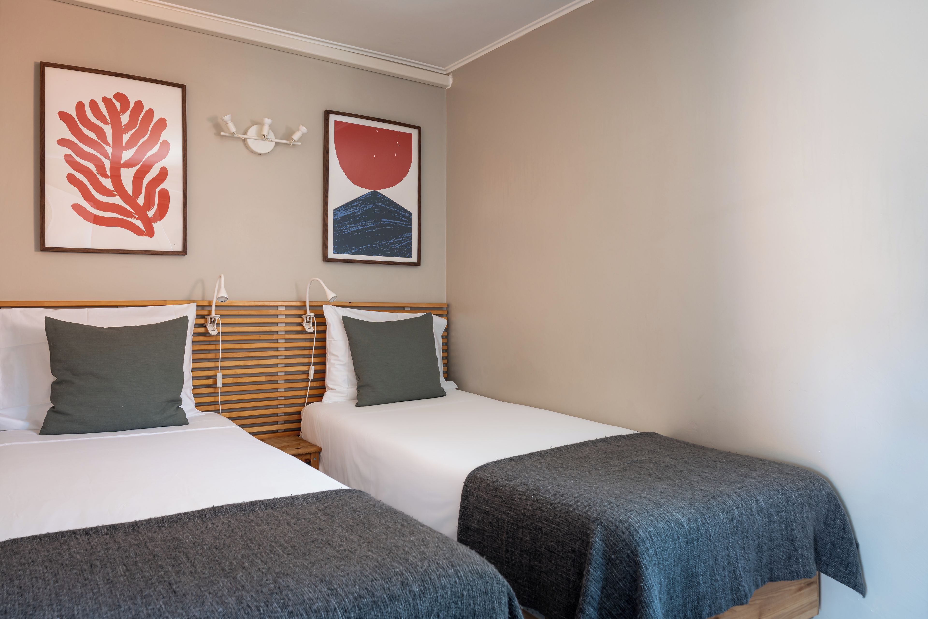 Een hotelkamer met twee bedden, een houten hoofdbord en kunst aan de muur.